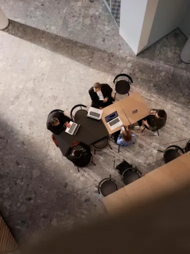 Konferensbord med arbetande människor och datorer sett ovanifrån.