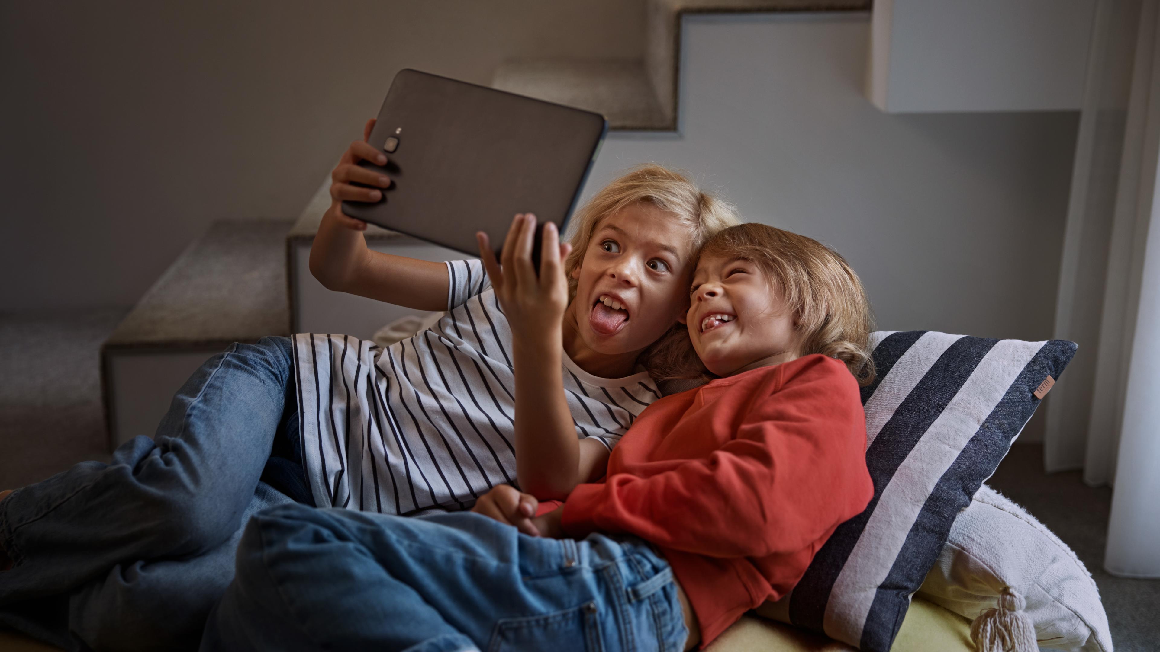 Två barn leker med en surfplatta.