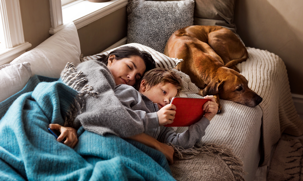 Mamma och pojke tittar på surfplatta i soffan.