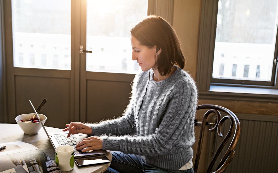 Kvinna arbetar vid laptop i hemmamiljö.