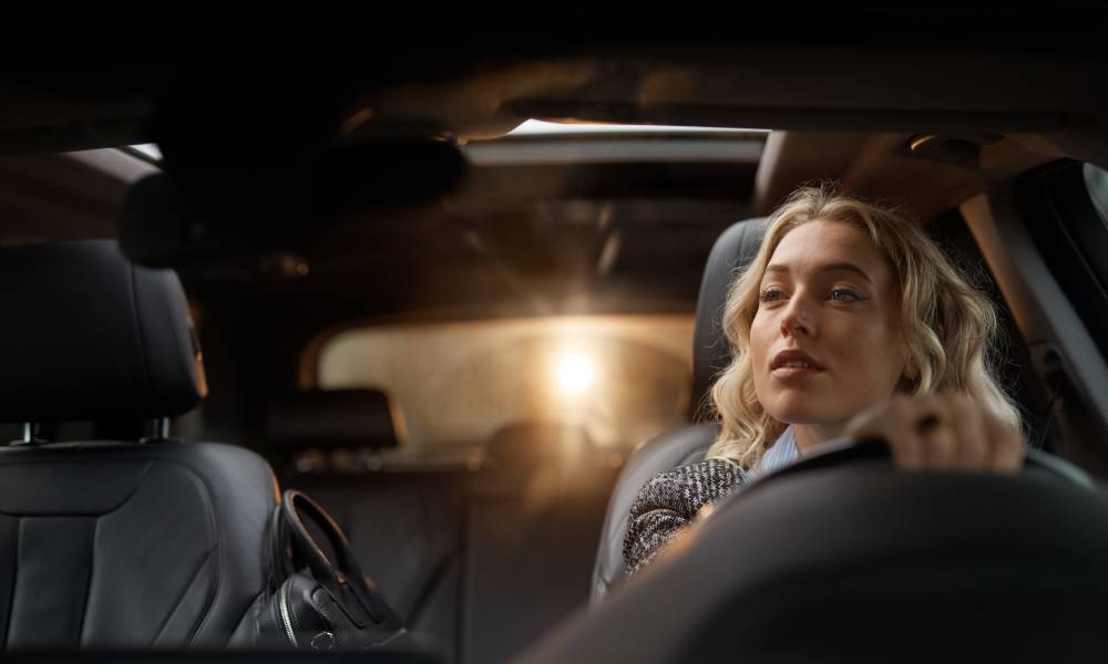 Kvinna som kör bil och tittar i backspegeln