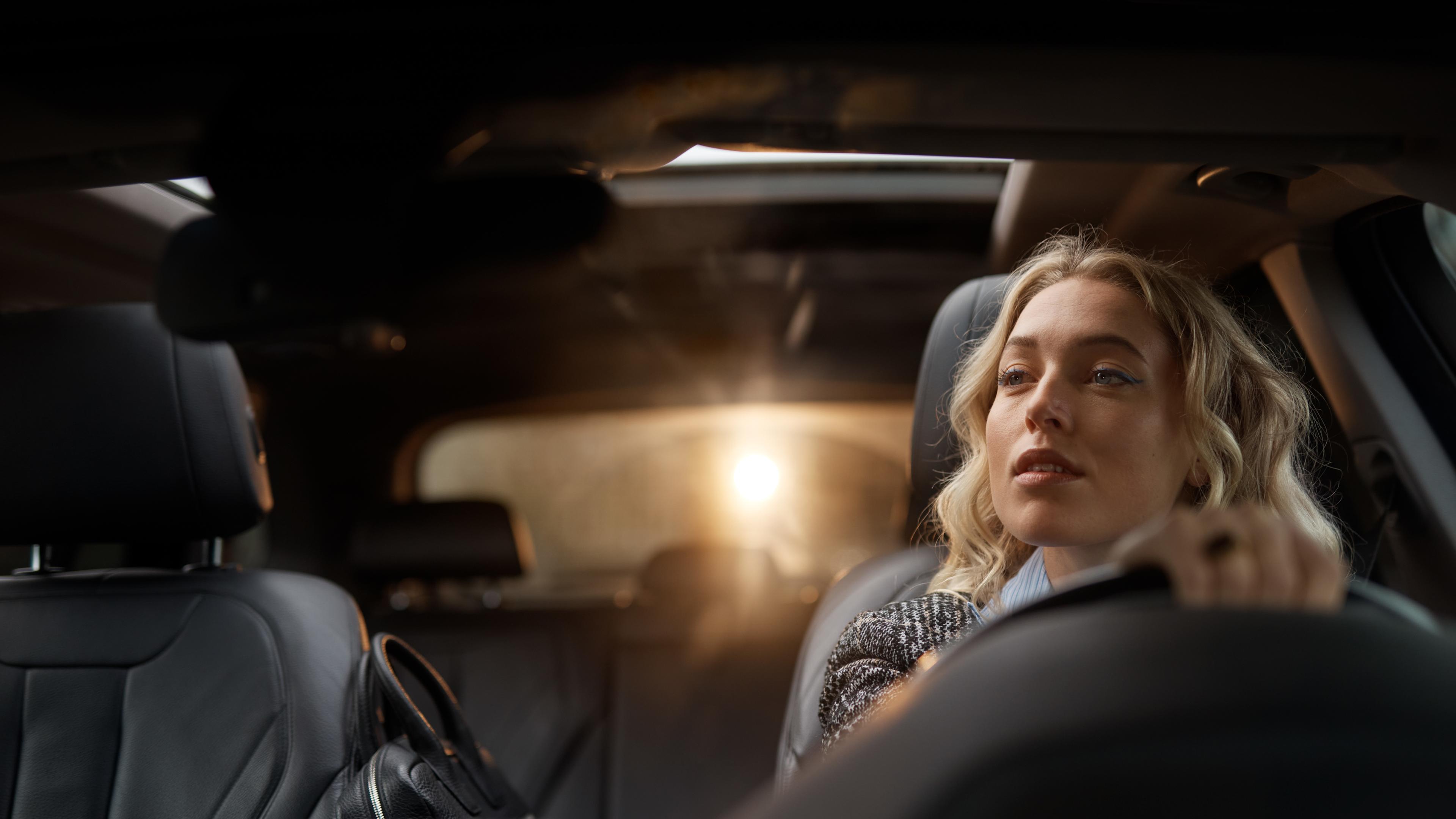 Kvinna som kör bil och tittar i backspegeln