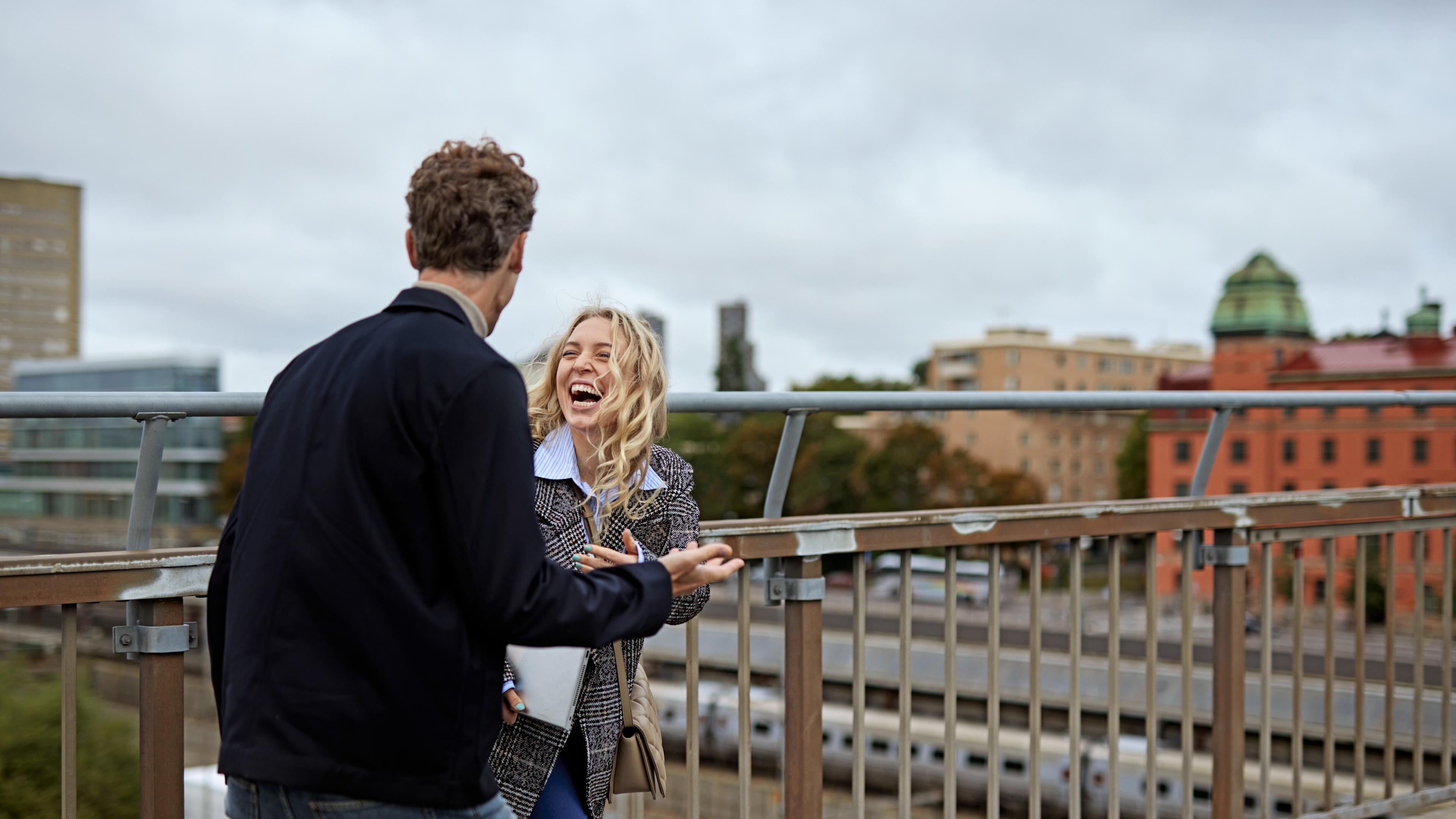 Kvinna och man pratar på takterrass i Stockholm.