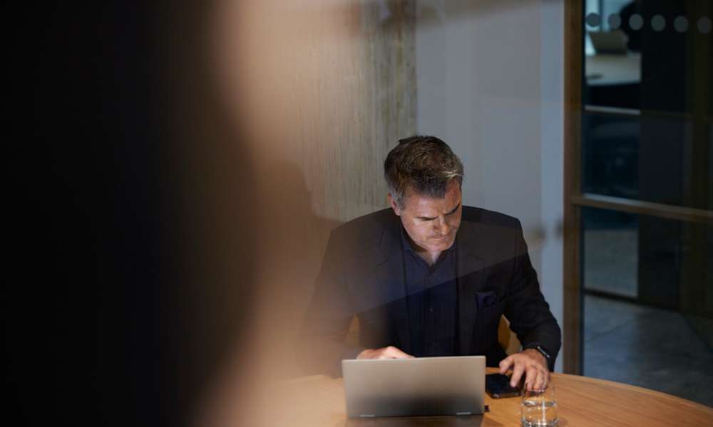 Man på kontor med laptop och mobil