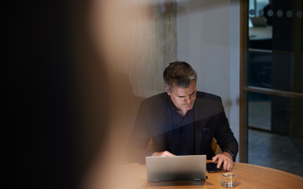 Man på kontor med laptop och mobil.