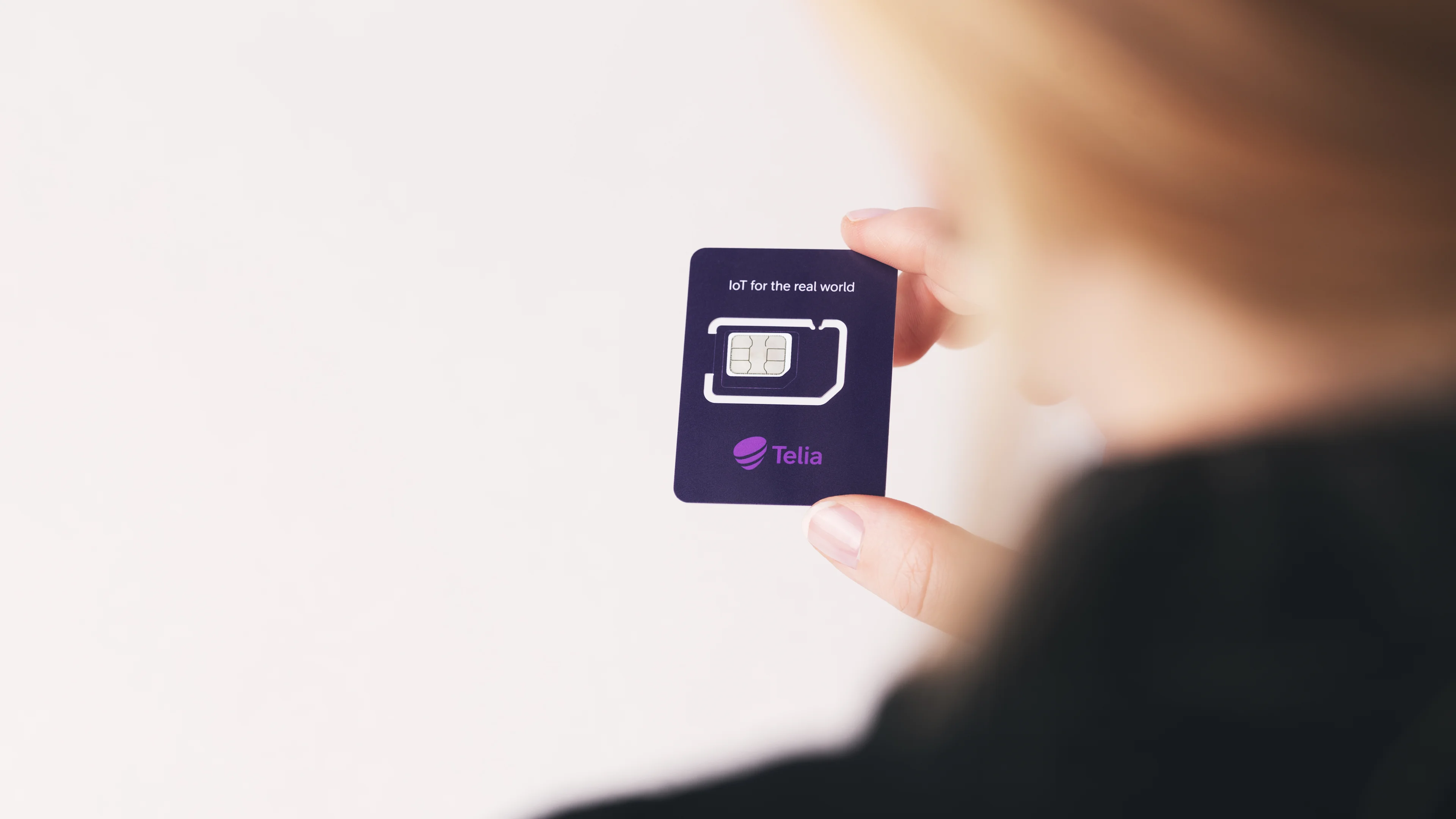 Person som håller i ett IoT-simkort