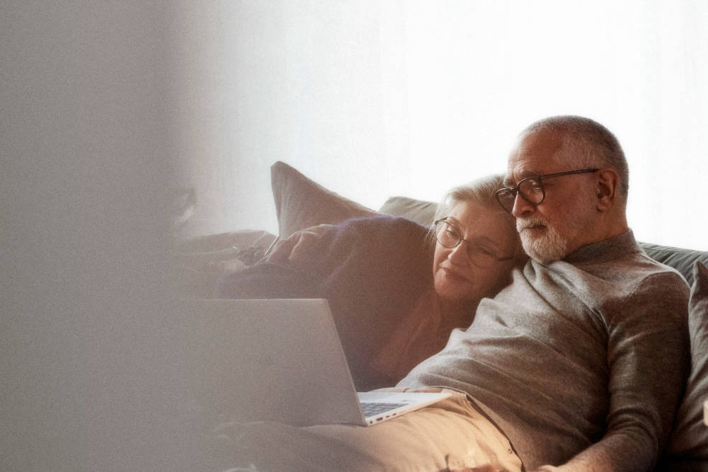 Telia_company_reinvention_14 - äldre par tittar på laptop i vardagsrumsmiljö - senior - hårt beskuren