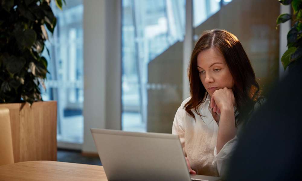 Kvinna som betraktar datorskärm med handen på hakan.