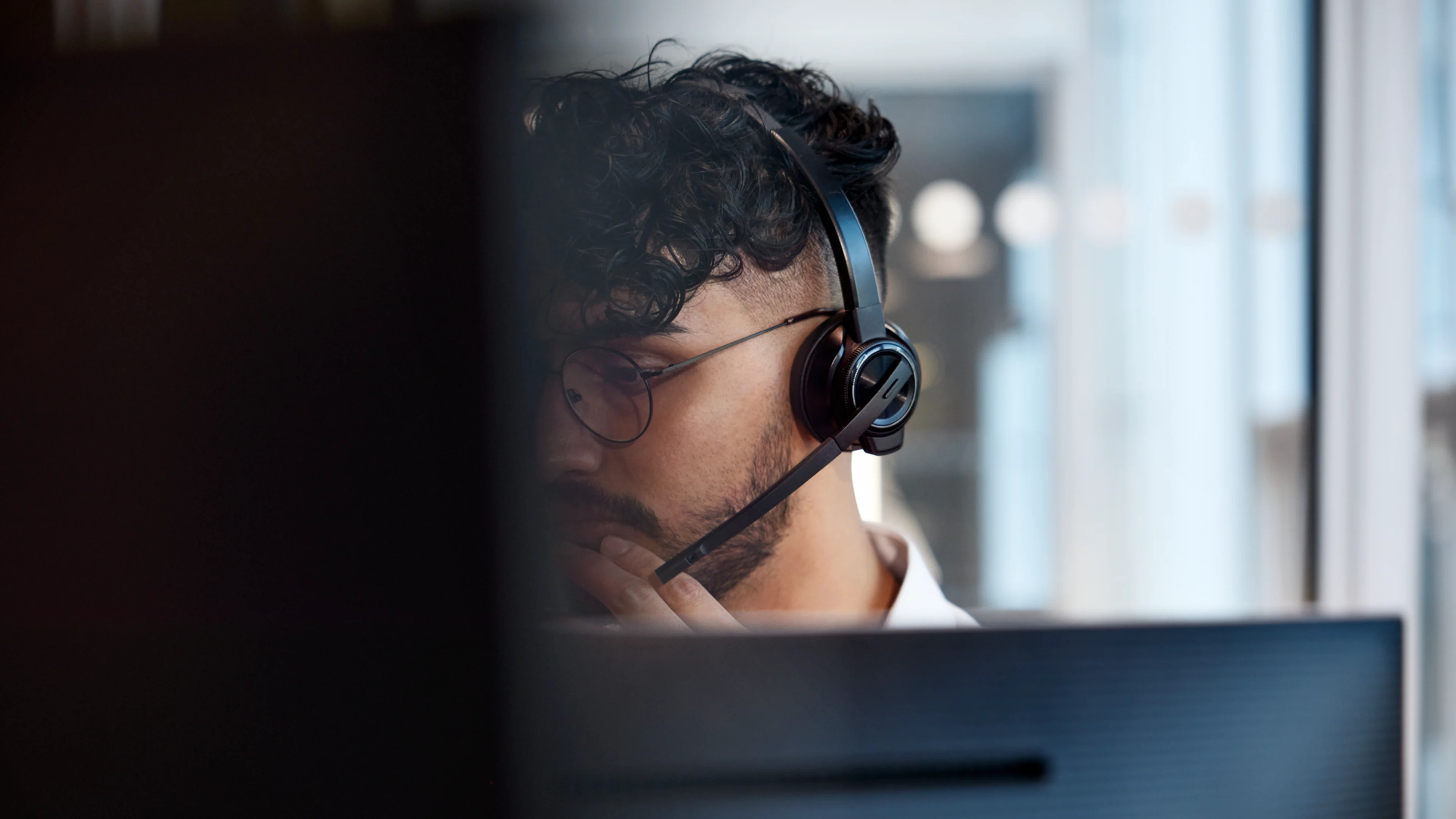En man med hörlurar som tittar på en dator.