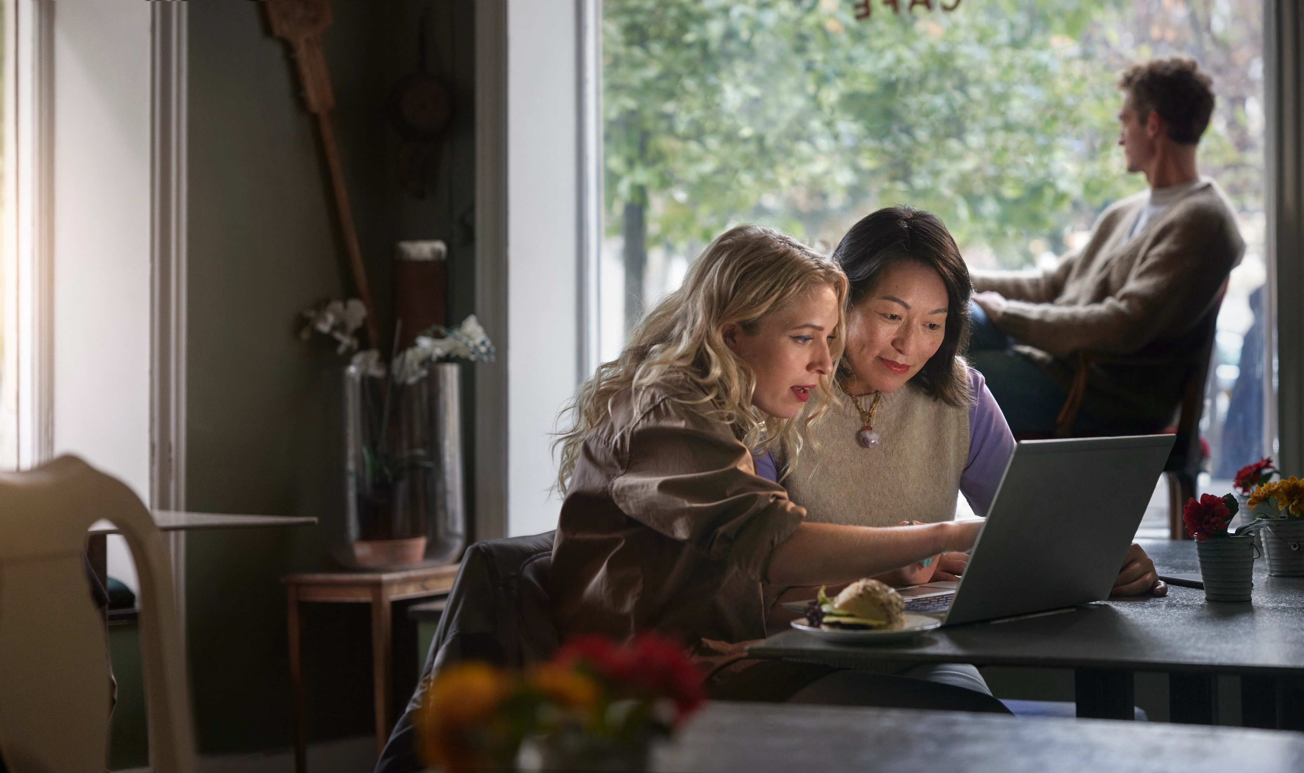 Två personer på café sitter framför laptop tillsammans. 