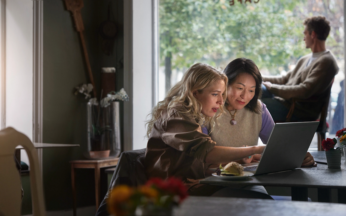 Två personer på café sitter framför laptop tillsammans.