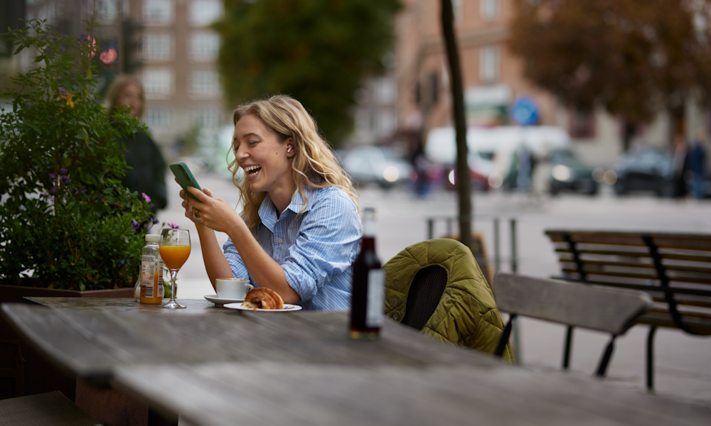 Kvinna arbetar med mobil i Telias nät på café