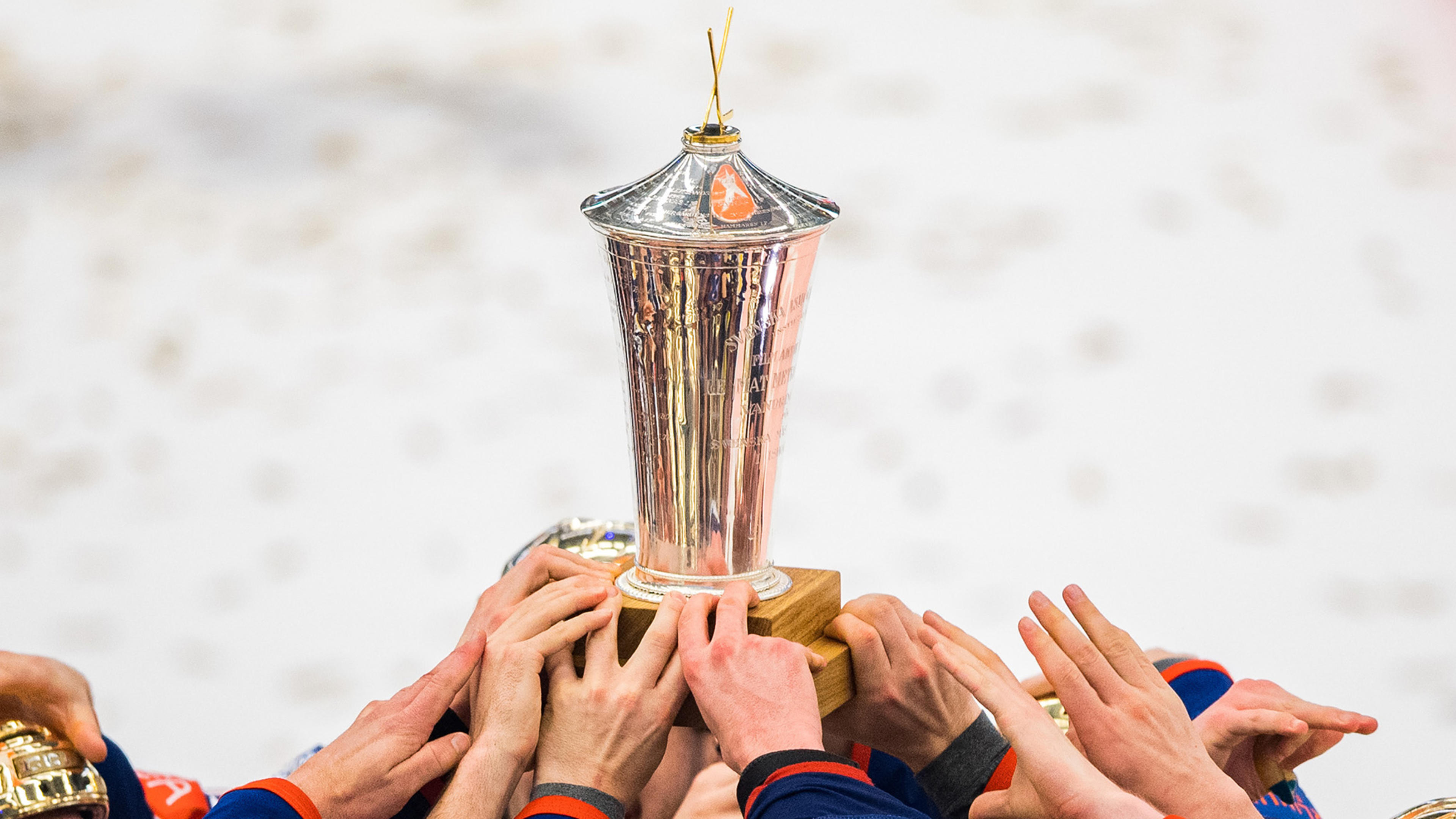 Bild på SHL-pokalen och spelare som höjder den i luften. Många lag har varit svenska mästare i Svenska Hockeyligan genom tiderna.