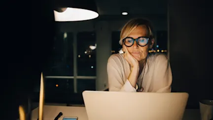 Kvinna som sitter framför dator och tittar på skärmen.