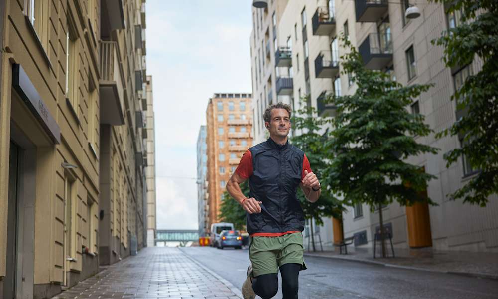 Man som springer på gata mellan hus