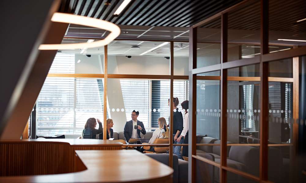 Personer som samtalar bakom glasvägg i ett konferensrum.