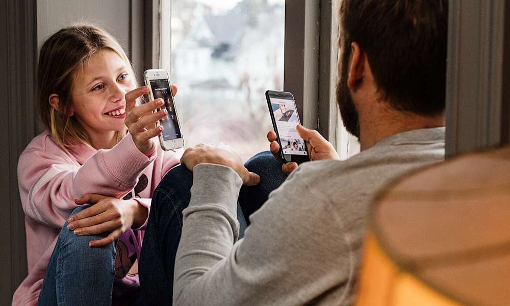 Flicka visar knapplåset på sin mobil för sin pappa.