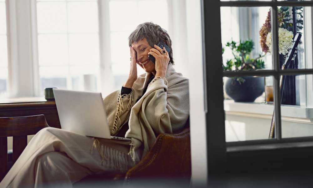 En glad äldre kvinna pratar i telefon och ler. 