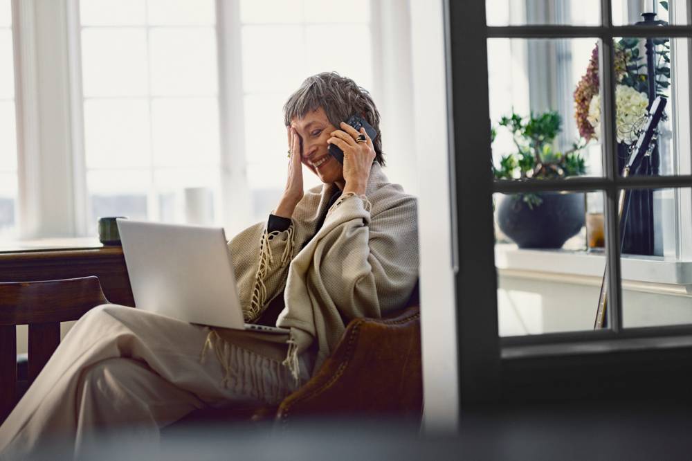 En glad äldre kvinna pratar i telefon och ler. 