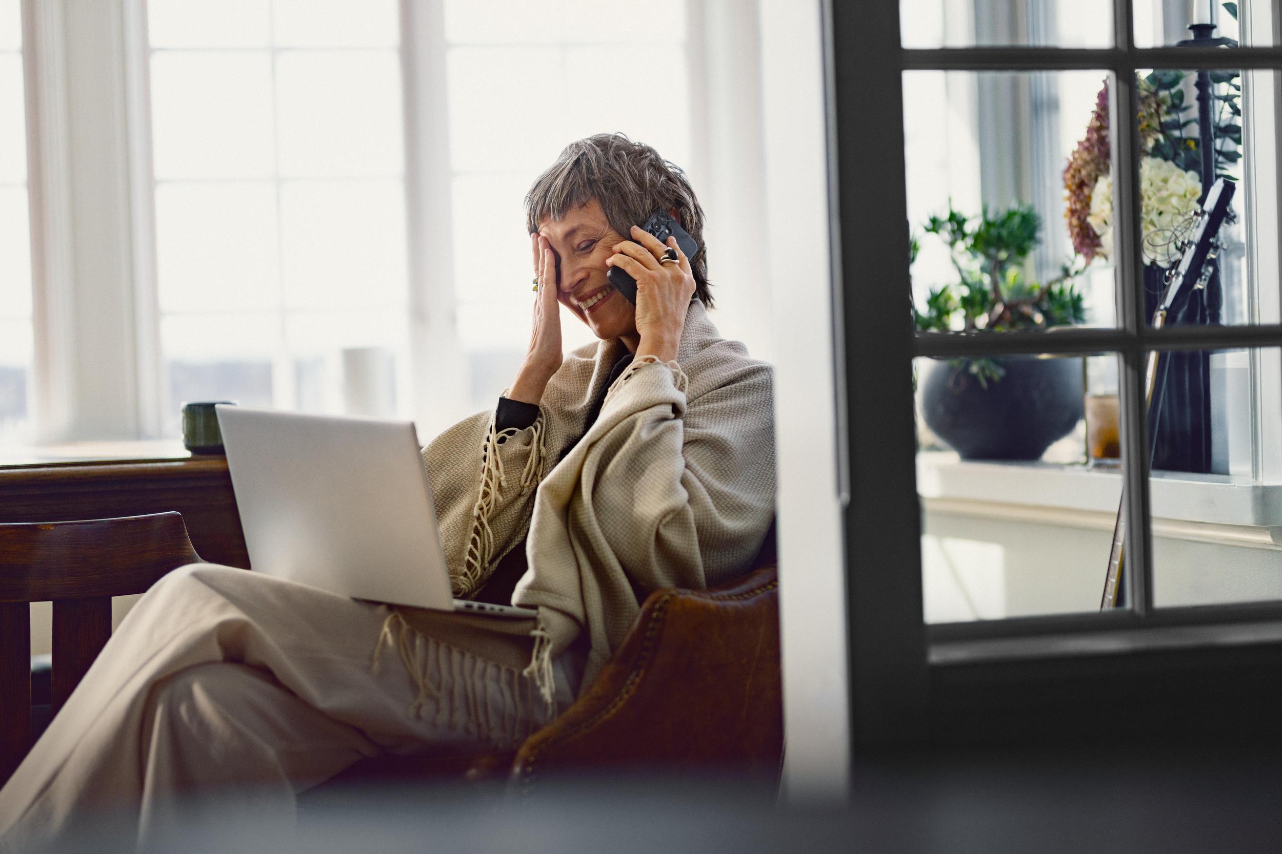 En glad äldre kvinna pratar i telefon och ler. 