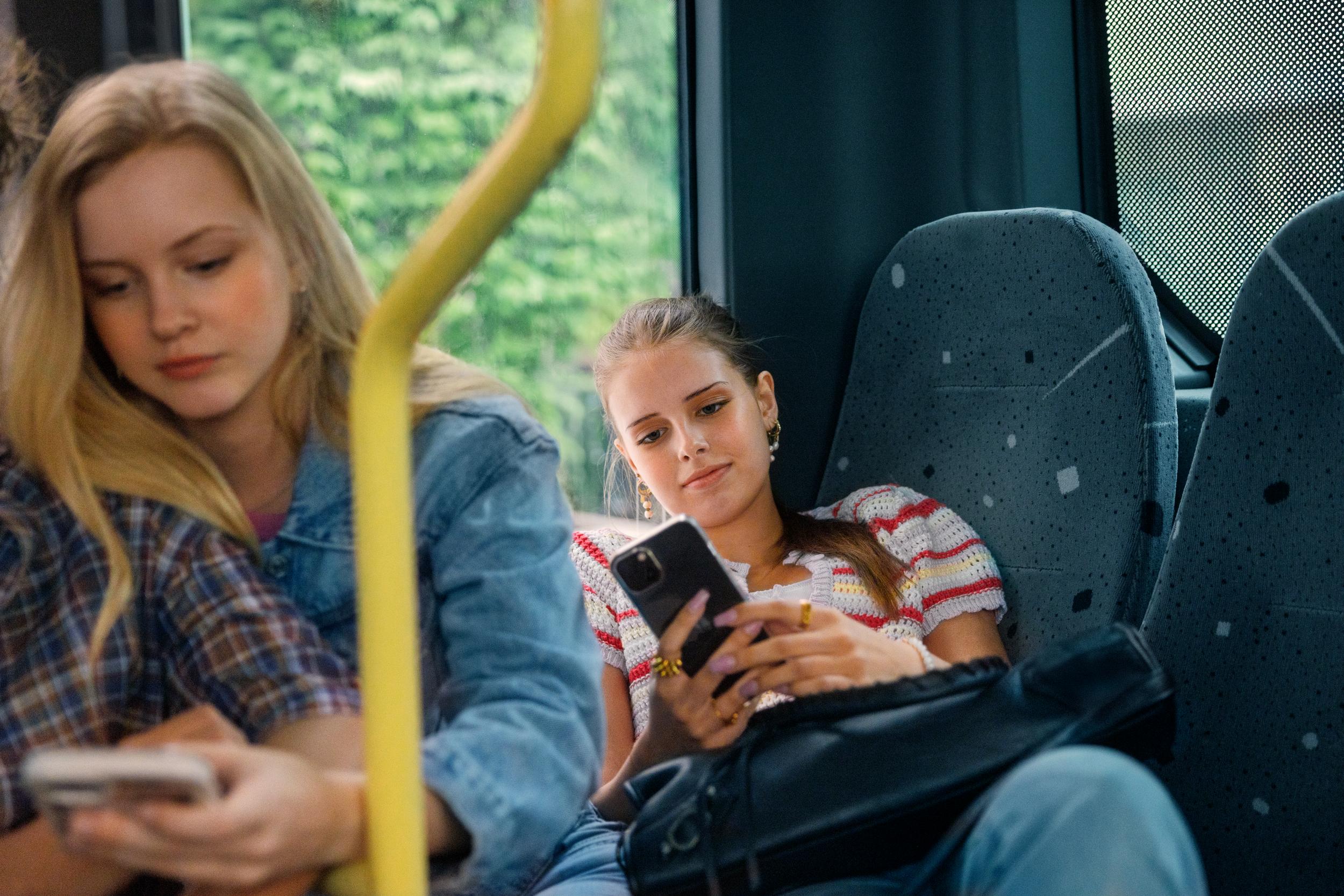 Personer som sitter på bussen och kollar i mobiltelefon