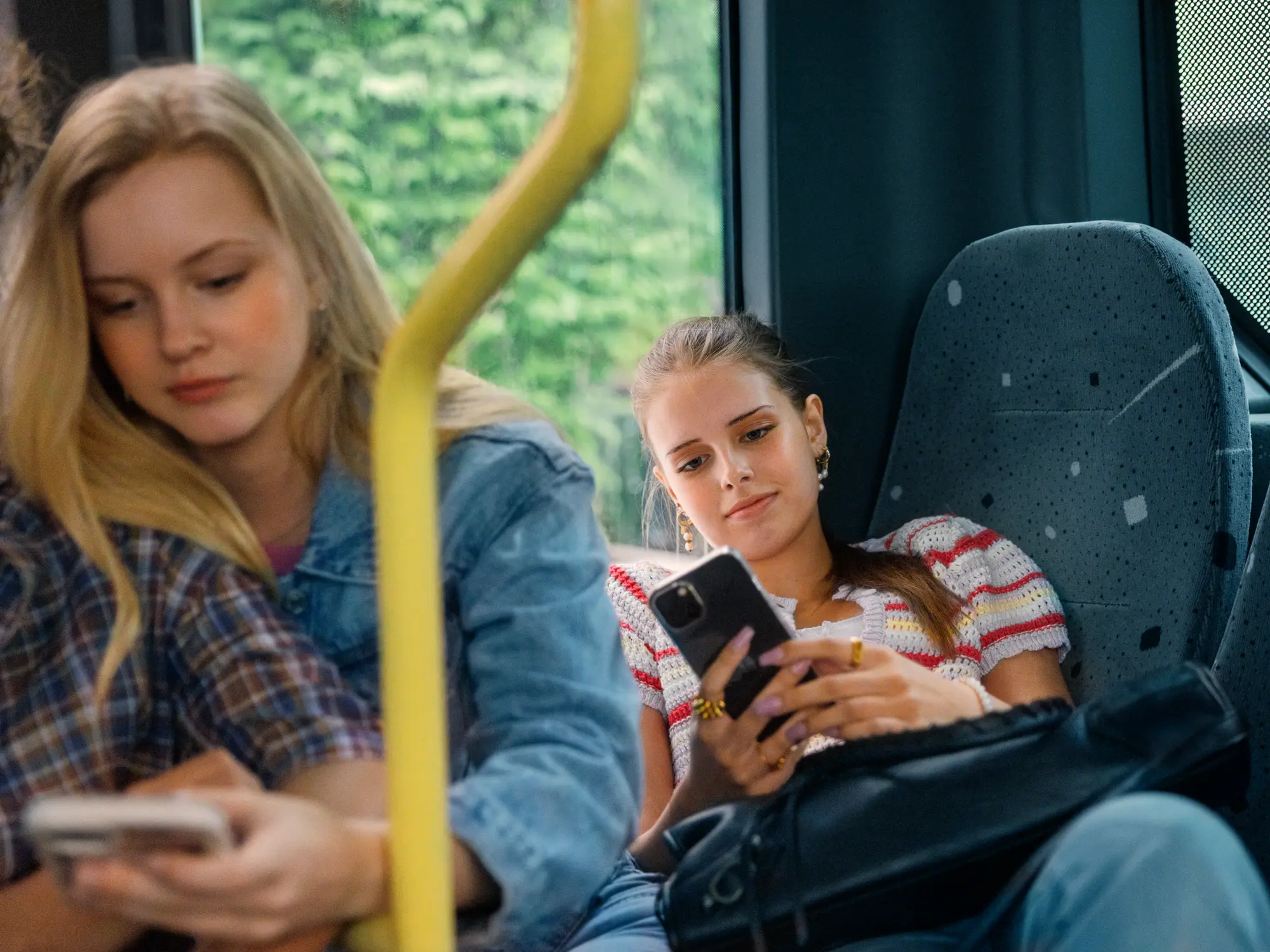Personer som sitter på bussen och kollar i mobiltelefon
