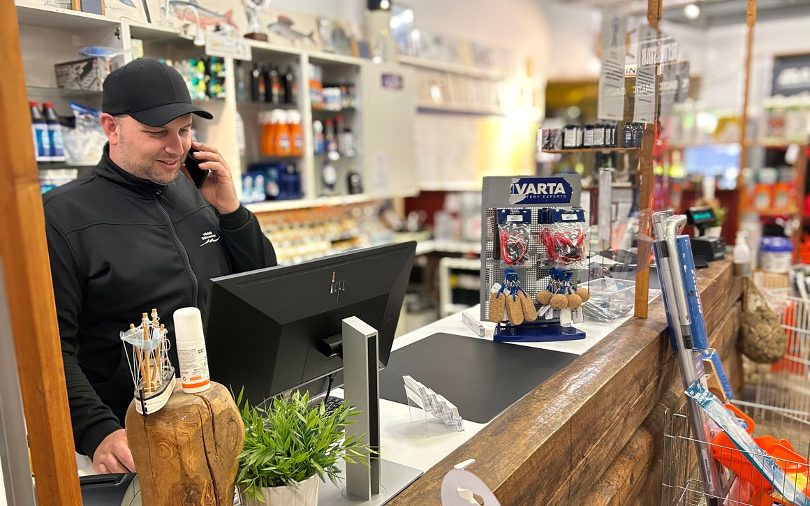Man i telefon bakom disken på båtfirman Väddö Båtcenter