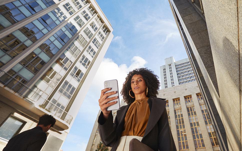 Business professional with company phone during work travel in an urban setting.
