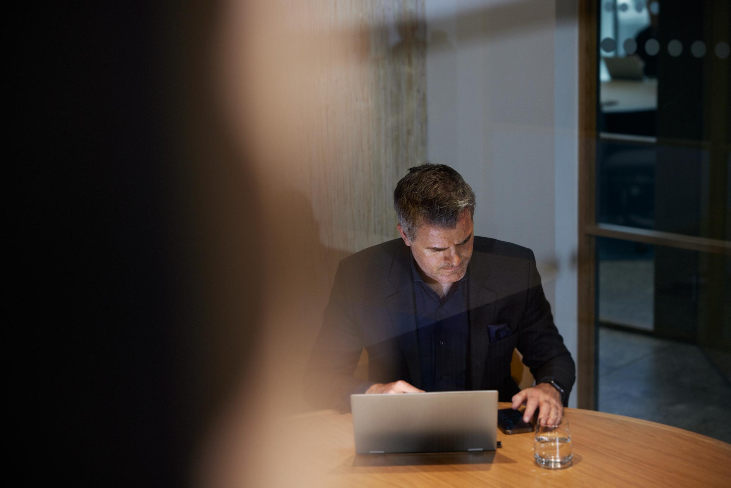 Man på kontor med laptop och mobil