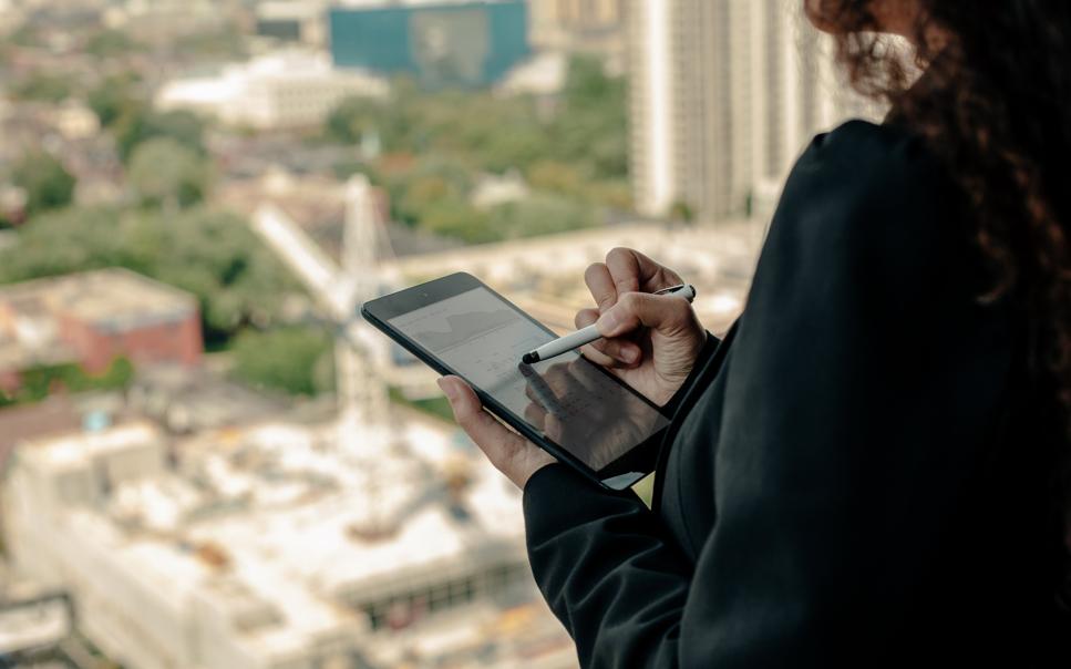 Kvinna som använder Ipad och står i ett fönster