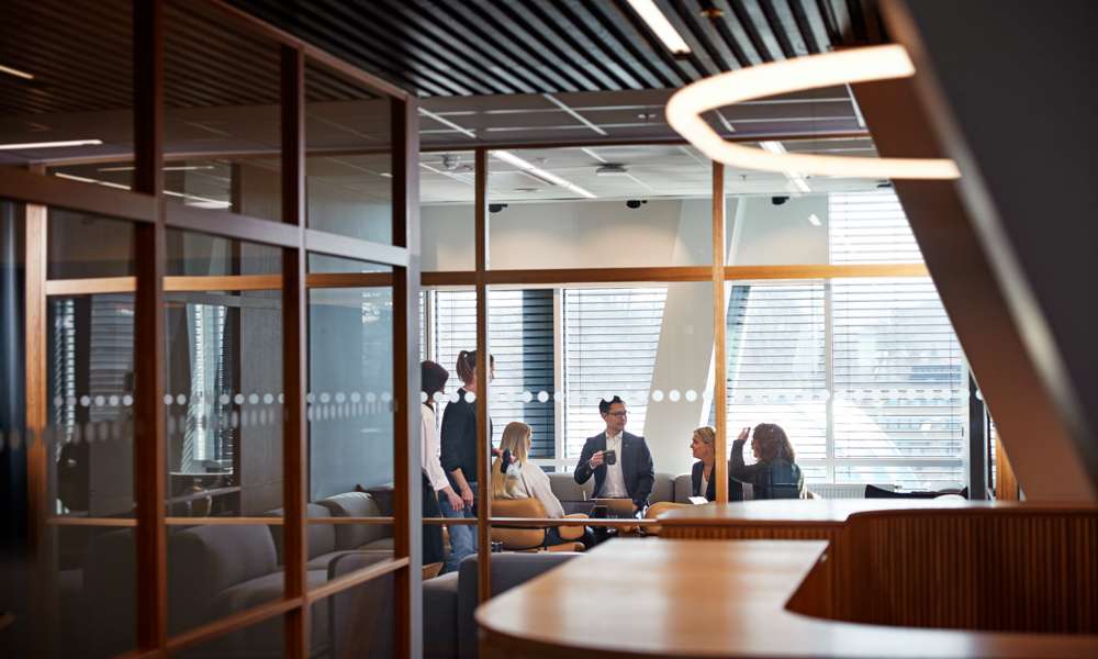 Personer som samtalar bakom glasvägg i ett konferensrum.