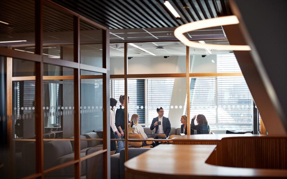 Personer som samtalar bakom glasvägg i ett konferensrum.