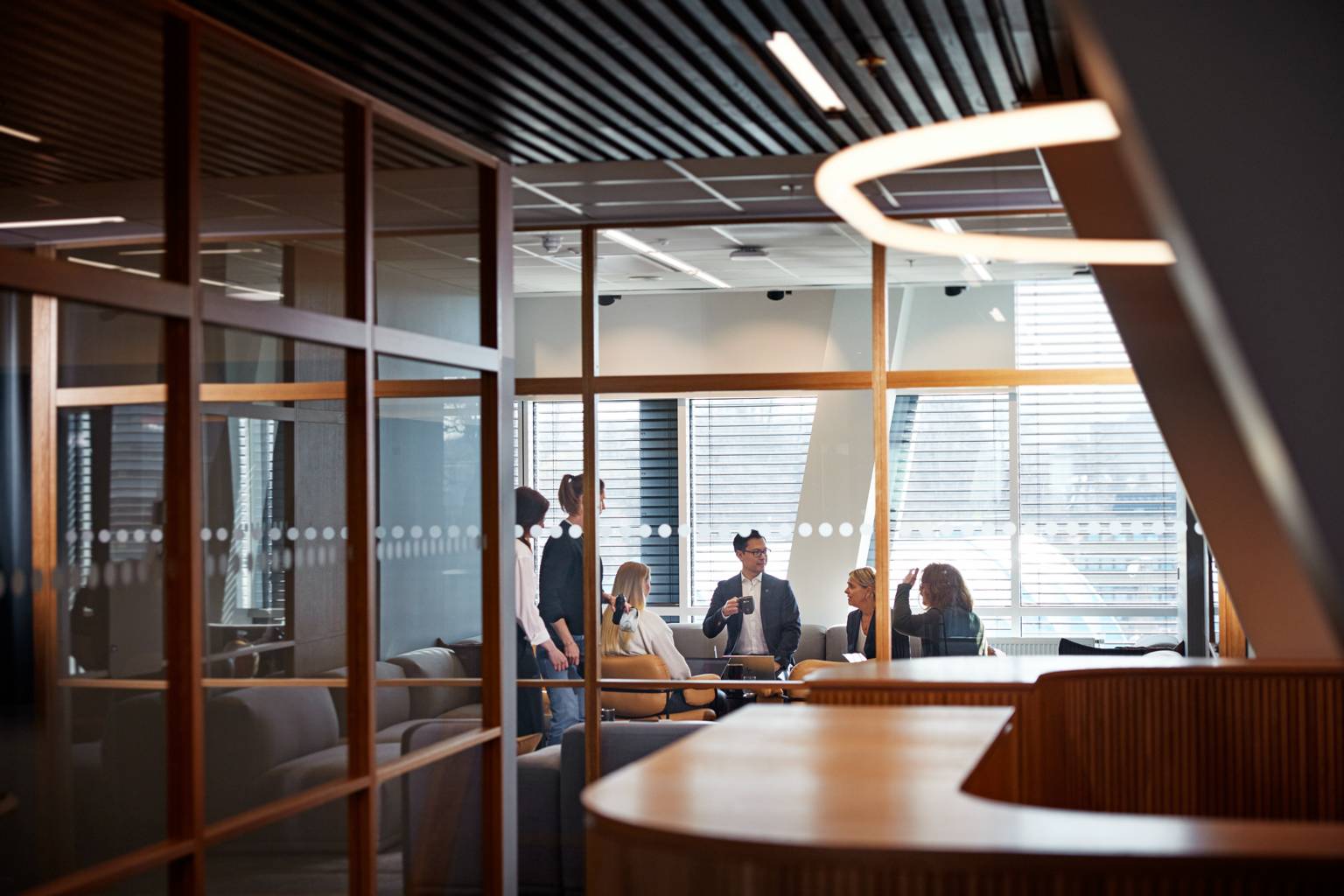 Personer som samtalar i ett konferensrum med väggar av glas.
