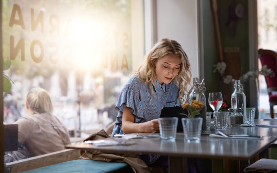 Kvinna arbetar på sin surfplatta vid ett restaurangbord.