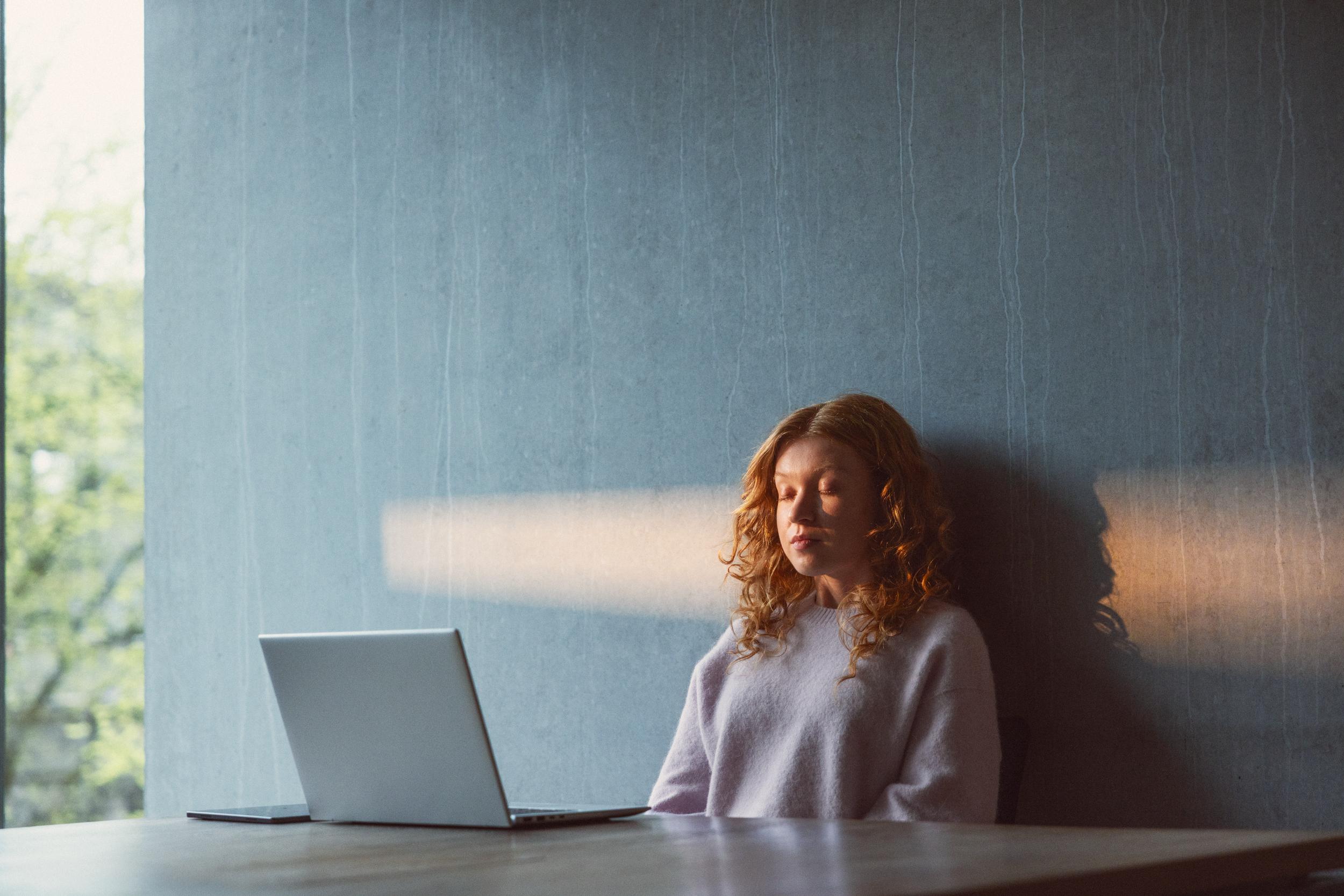 En kvinna som blundar framför en wifi-uppkopplad laptop.