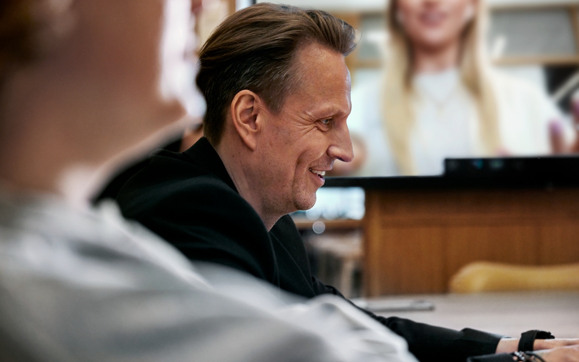 Man ler framför dator