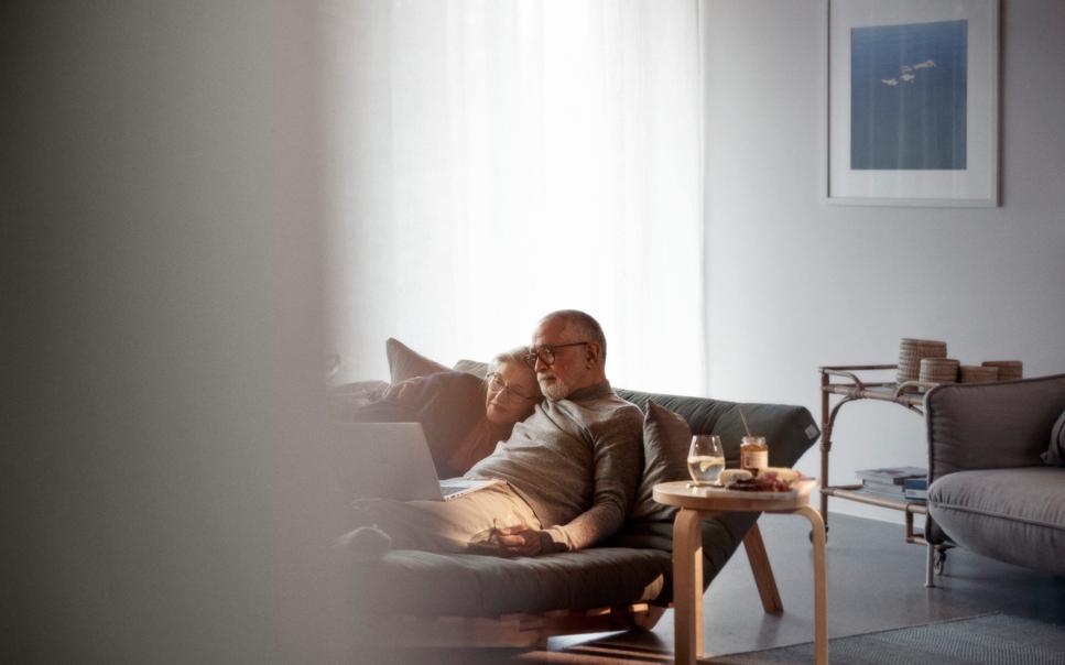 Äldre par tittar på en bärbar dator tillsammans i vardagsrumsmiljö.