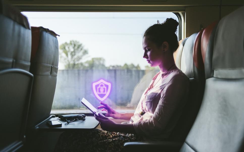 Kvinna ser bekymrad ut med ipad på tåg. Lila neonbanner för cybersäkerhet infälld.