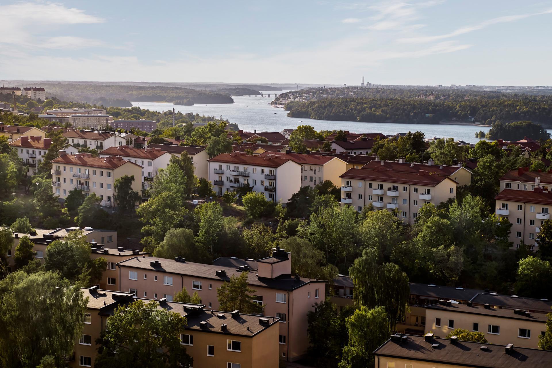 Flygbild över flervåningshus omgivna av skog.