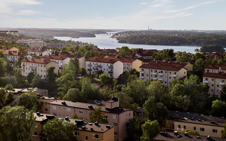 Flygbild över flervåningshus omgivna av skog.