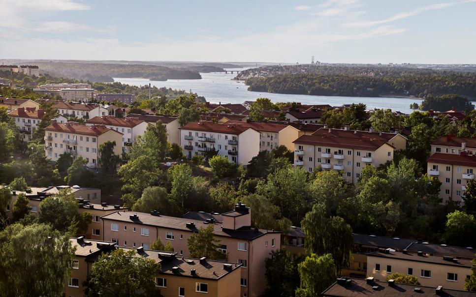Flygbild över flervåningshus omgivna av skog.