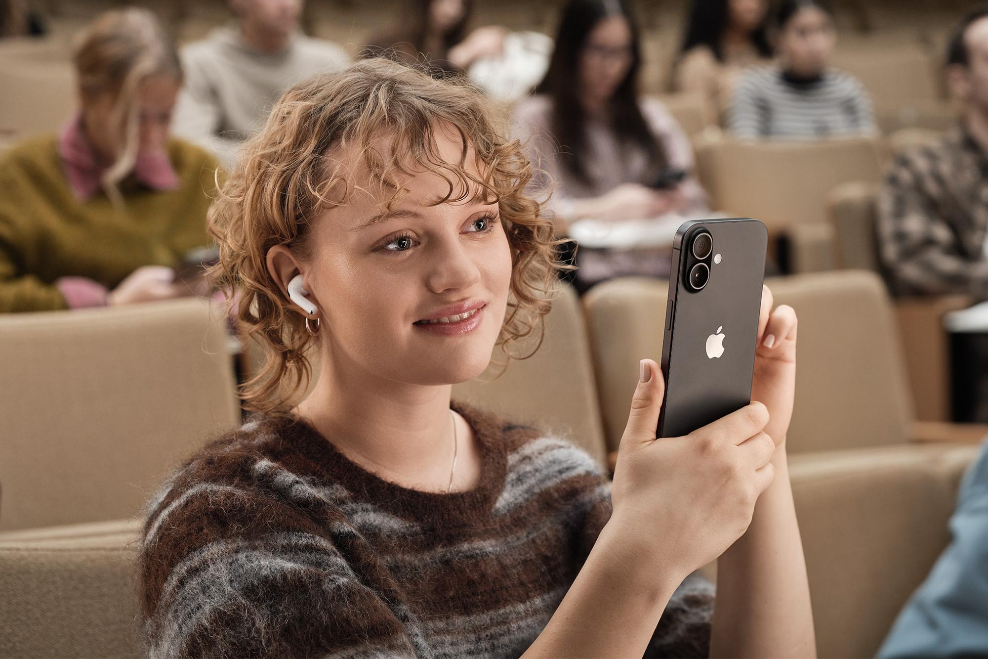 Kvinna med hörlurar håller i svart iPhone 17