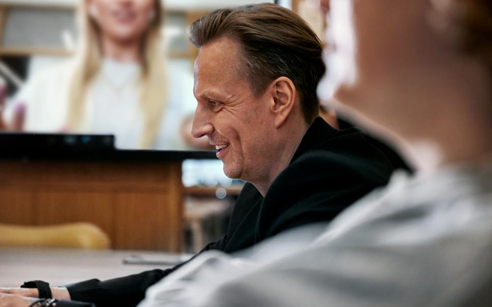 Man sitter vid dator på kontor i videomöte med kollegor.