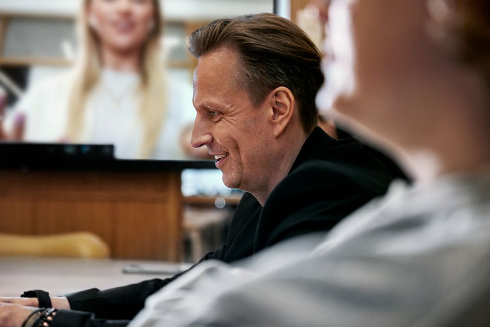 Man sitter vid dator på kontor i videomöte med kollegor.