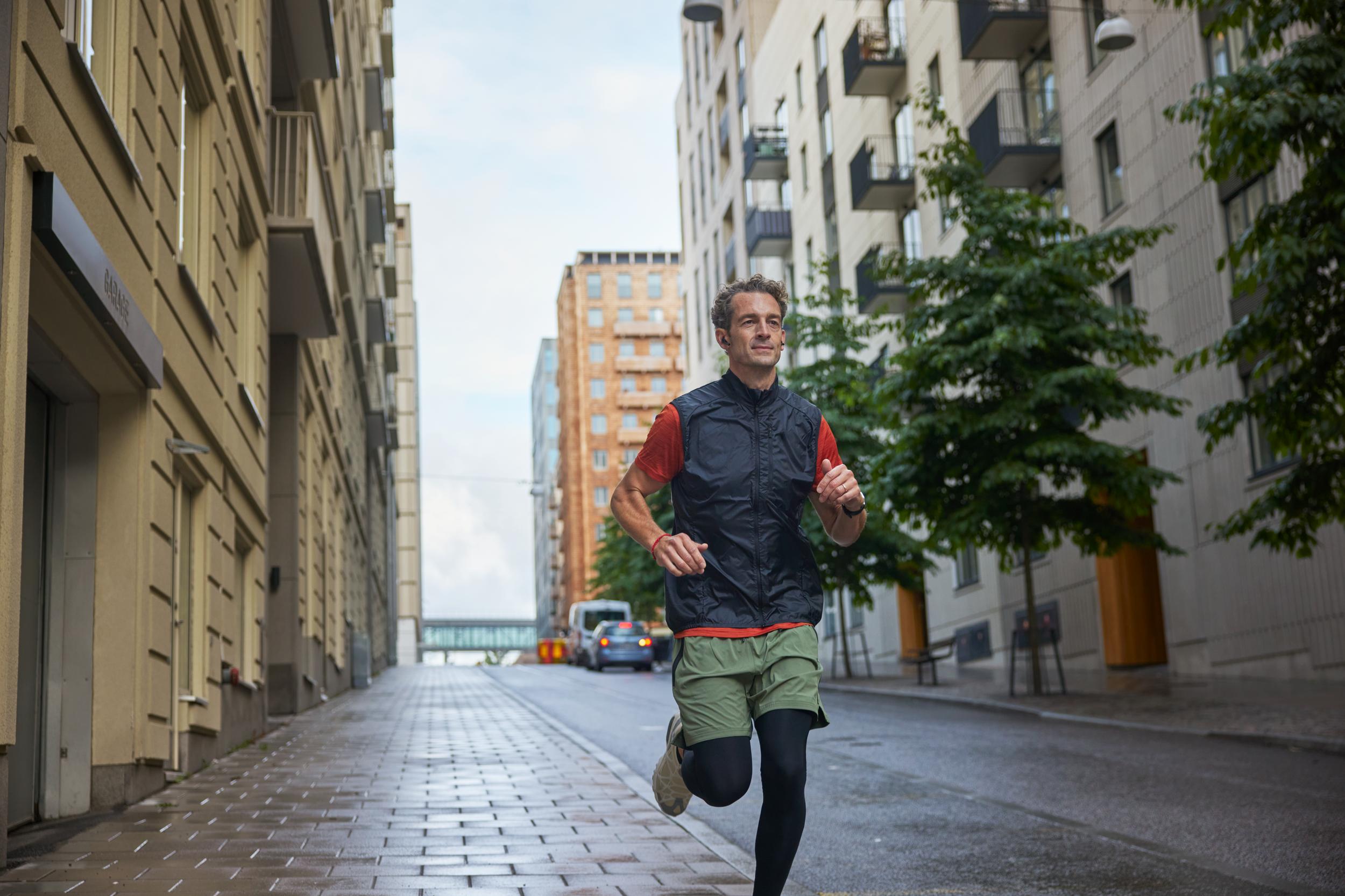 Man som springer på gata mellan hus