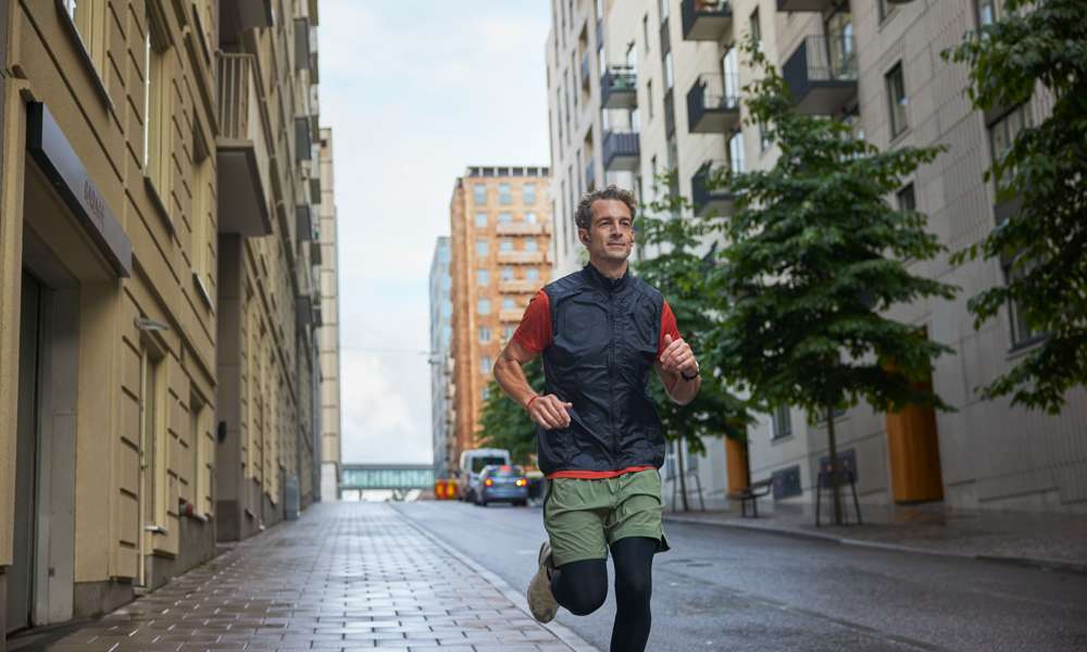 Man som springer på gata mellan hus