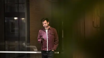 Avslappnat klädd man håller i telefon med företagsabonnemang på kontor