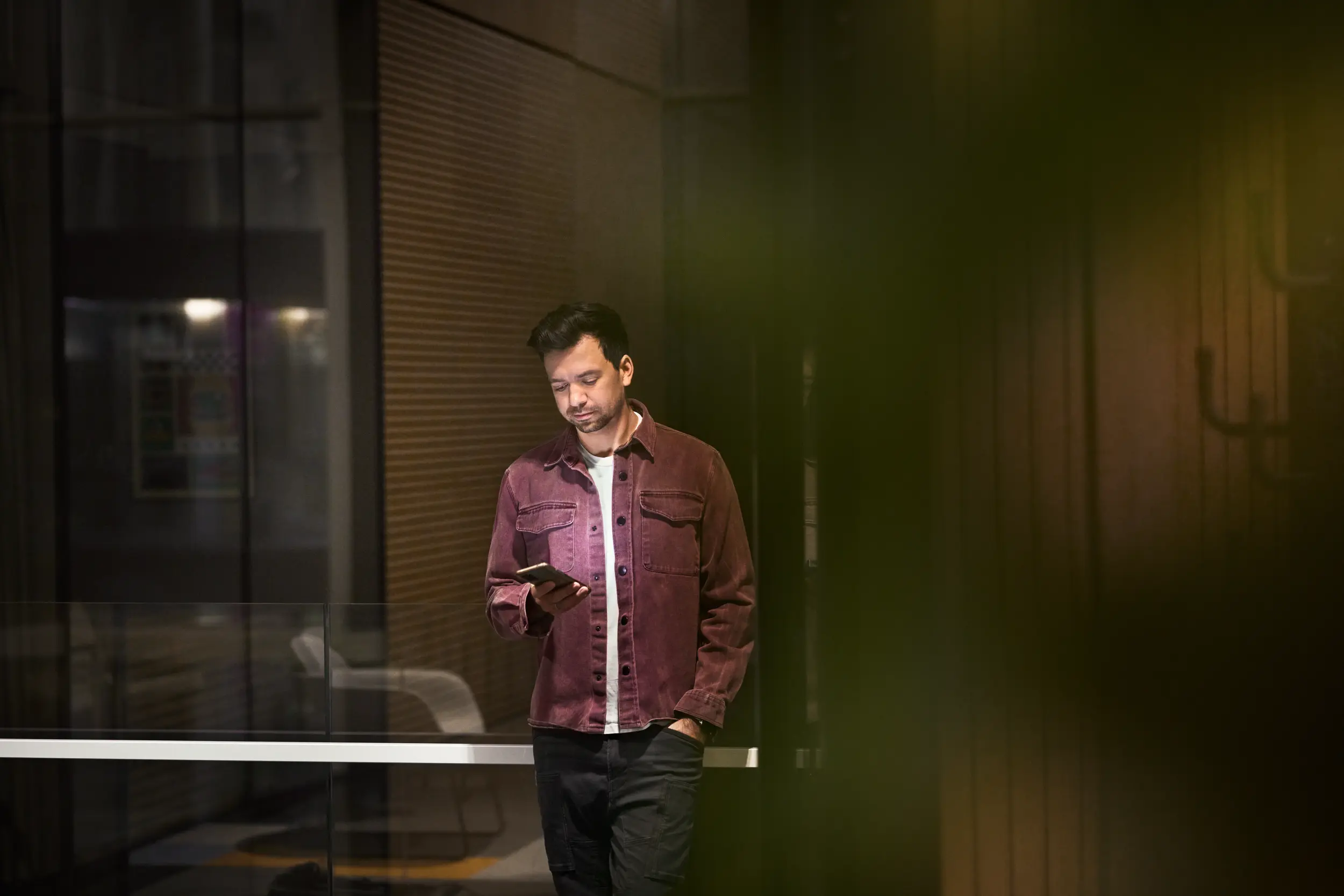 Avslappnat klädd man håller i telefon med företagsabonnemang på kontor