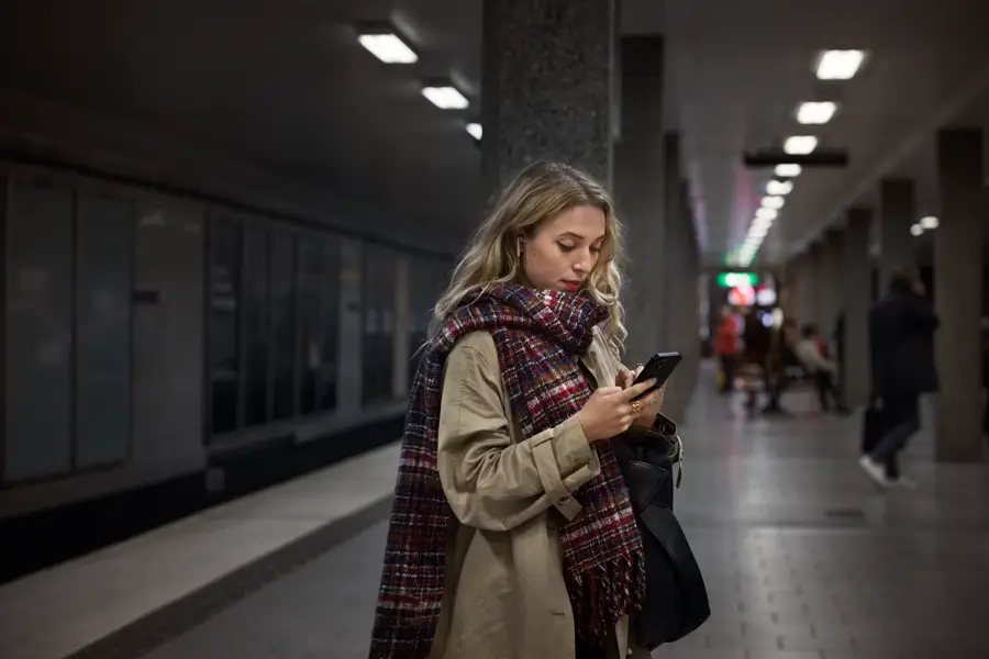 En kvinna som tittar ner i sin mobiltelefon.