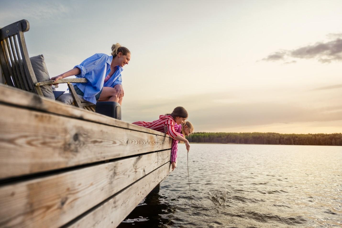 Mamma och barn fiskar från brygga